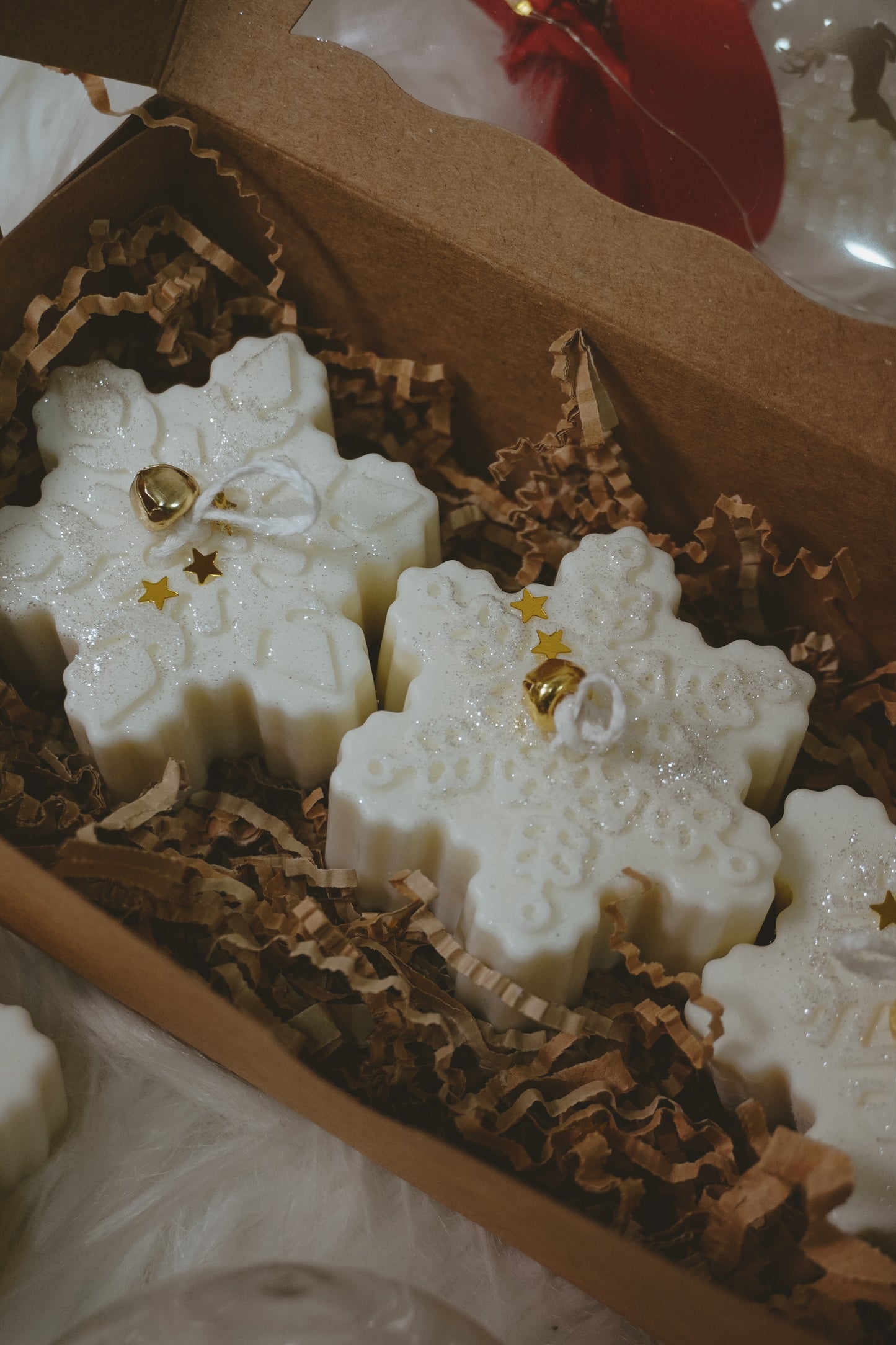 Snowflake-shaped white candies with gold decorations in a brown box.
