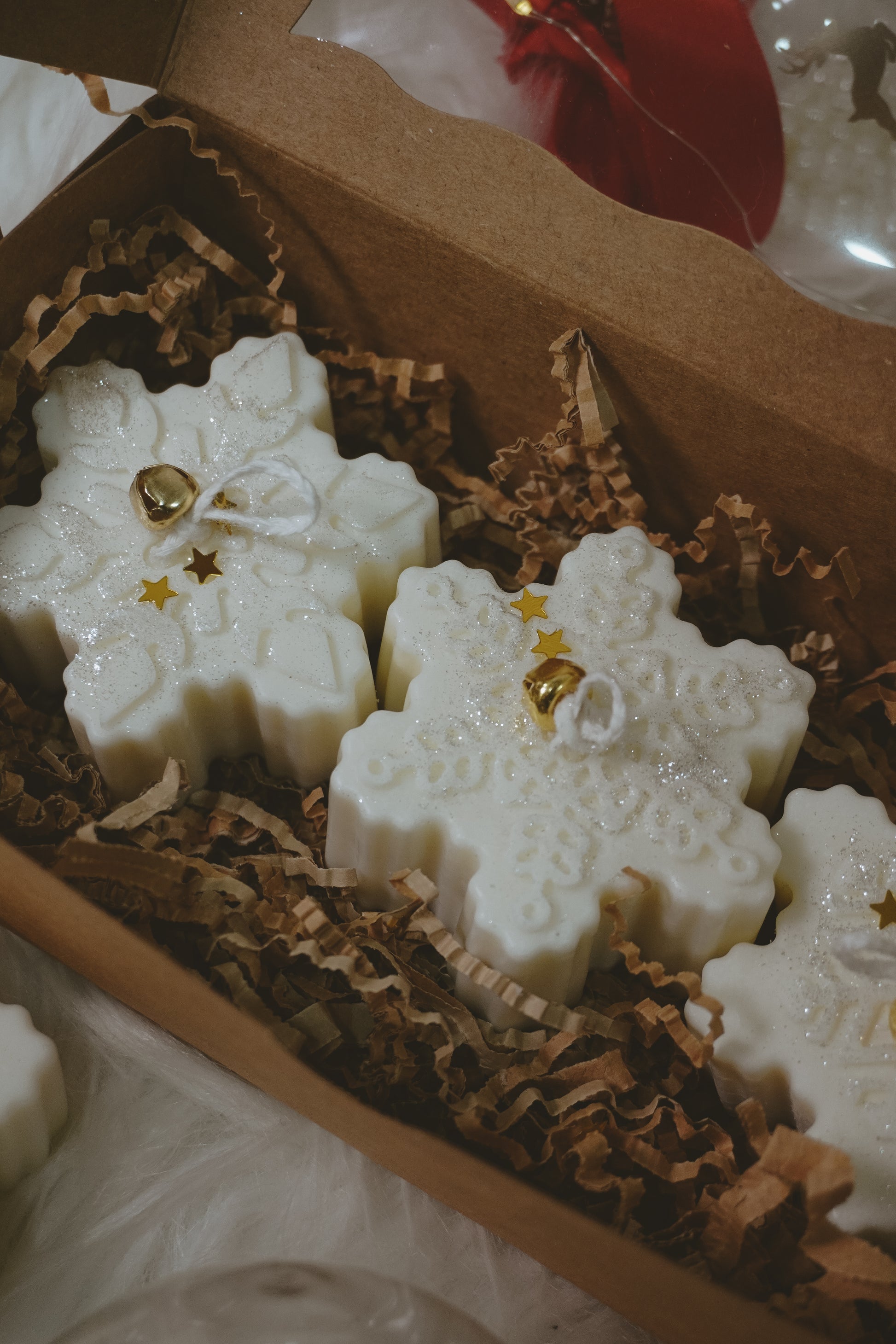 Snowflake-shaped white candies with gold decorations in a brown box.